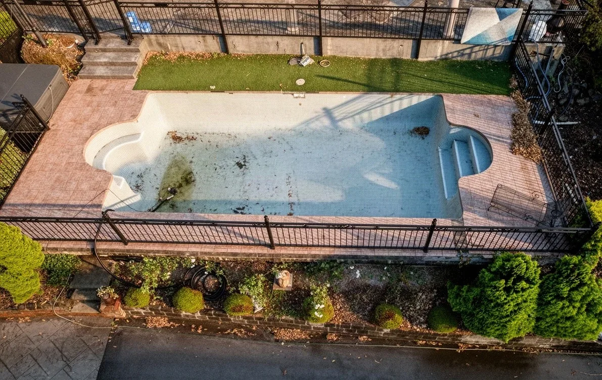 The same backyard before the work, the pool drained and stained