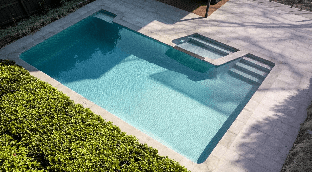 A tiled pool with a green ceramic interior and granite paving