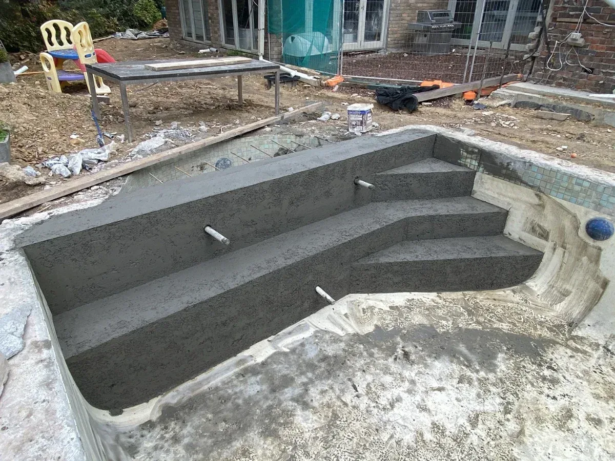 New concrete steps and a bench formed inside an existing pool shell