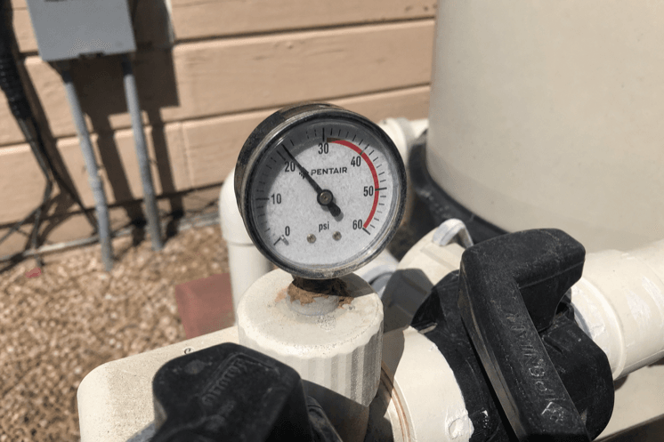 A pressure gauge on pool filter plumbing
