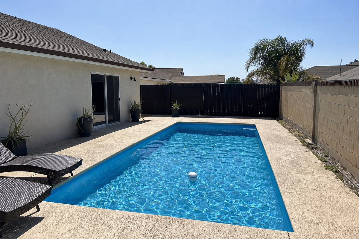 An unshaded backyard pool in the San Fernando Valley in hard afternoon sun, with a floating chlorine tablet dispenser in the middle of the water