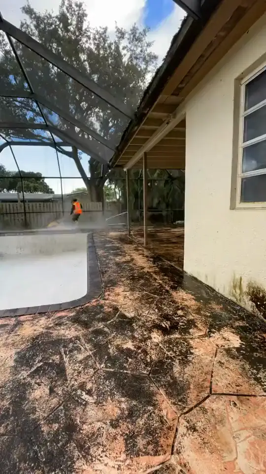 Pressure washing a screened pool deck back to clean