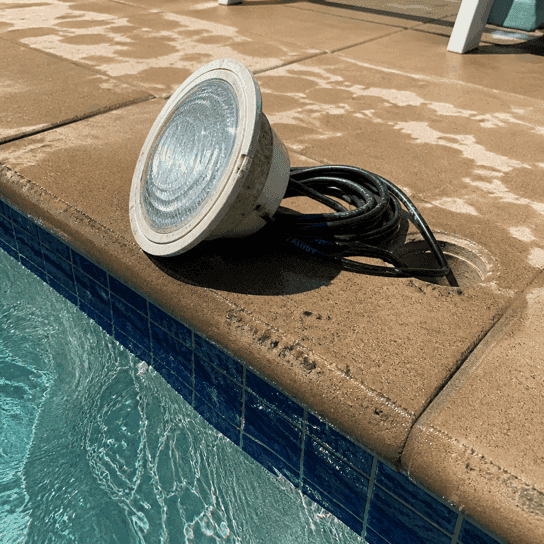A pool light pulled out onto the coping